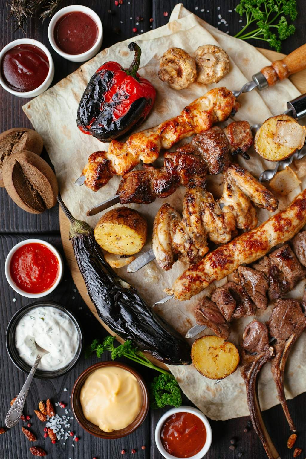 A platter of grilled meats and vegetables with several dipping sauces